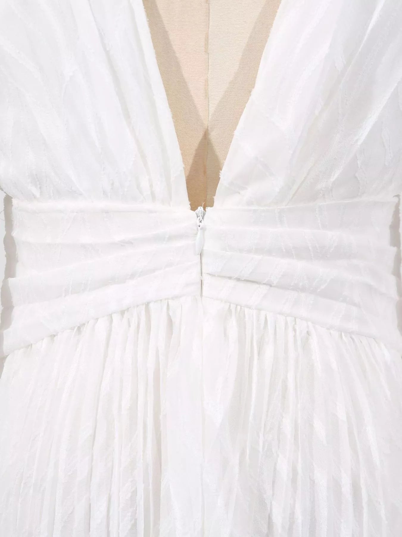NEWYORKLISTED STYLE COLLECTION: Close-up of a white dress with a deep neckline and bow detail.
