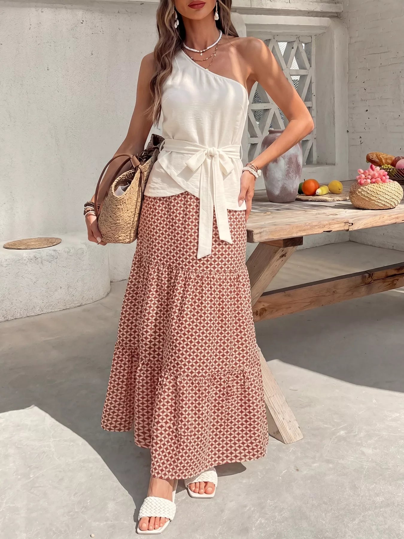 NEWYORKLISTED STYLE COLLECTION: Woman in a white top and patterned skirt standing in a bright outdoor setting.