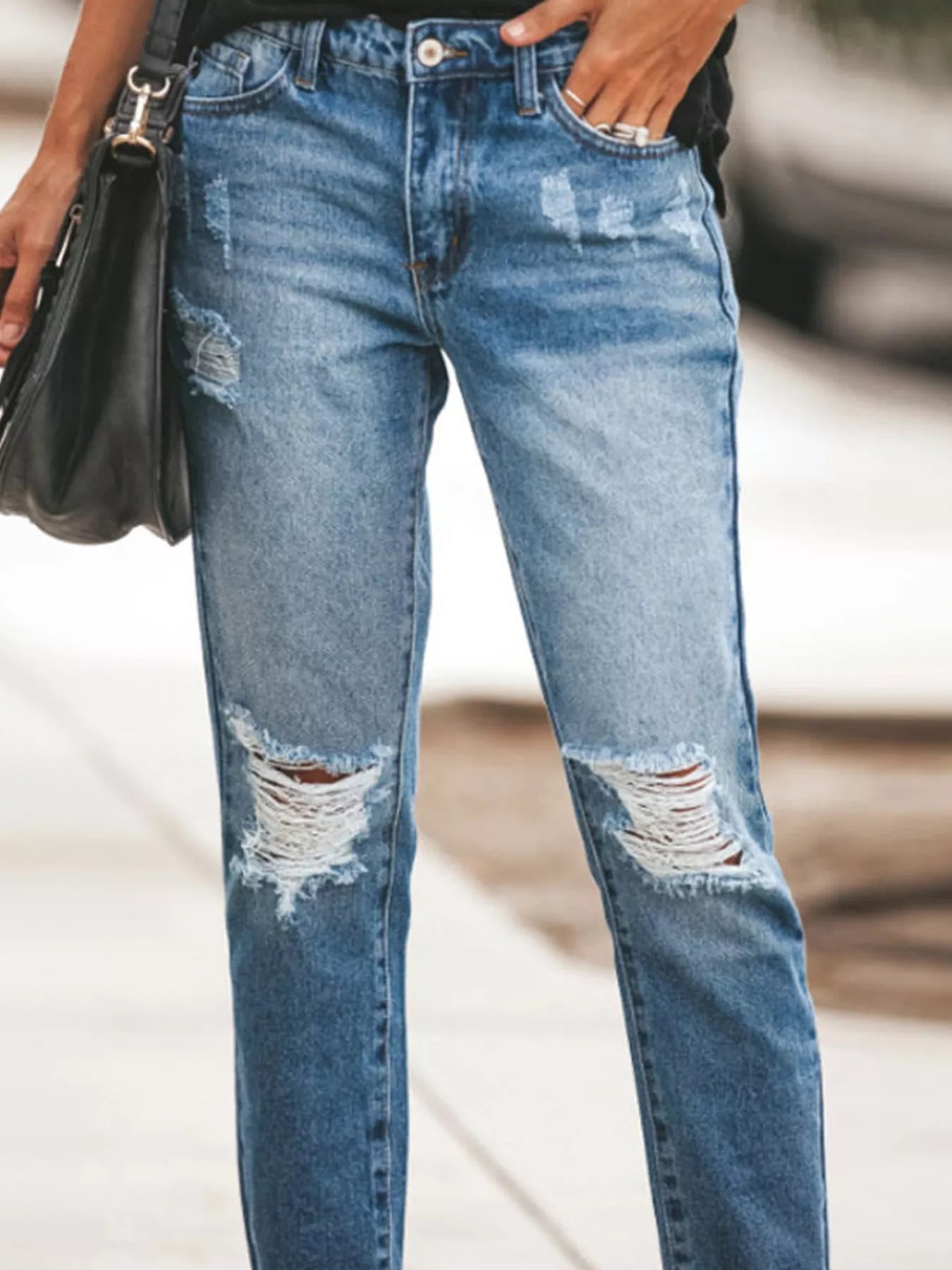 NEWYORKLISTED STYLE COLLECTION: Ripped blue jeans worn by a person with a blurred background