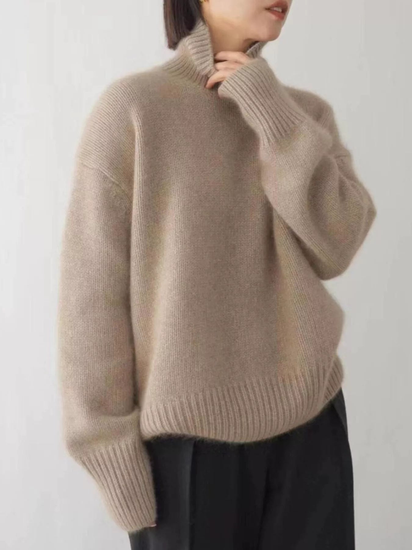 Person wearing a beige sweater against a plain background