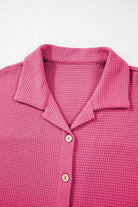 NEWYORKLISTED Comfort Collection: Close-up of a pink textured polo shirt with buttons on a light gray background