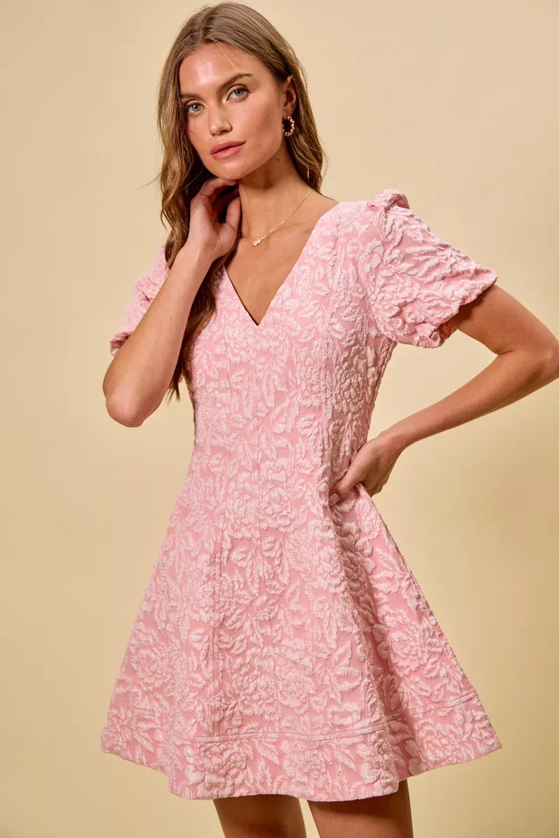 NEWYORKLISTED STYLE COLLECTION: Woman wearing a pink dress with ruffled sleeves against a beige background