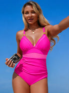 NEWYORKLISTED STYLE COLLECTION: Woman in a pink swimsuit holding a camera against a blue sky.
