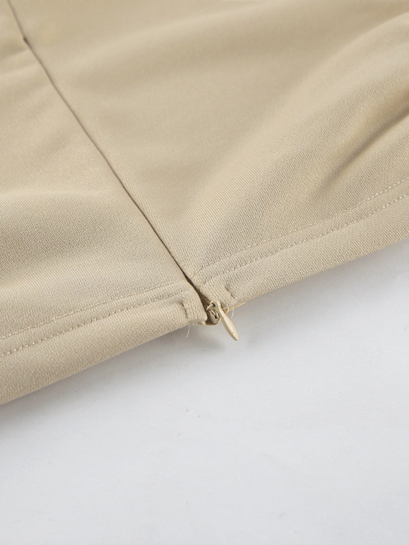 NEWYORKLISTED STYLE COLLECTION: Close-up of beige fabric with a zipper on a white background