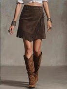 NEWYORKLISTED STYLE COLLECTION: Person wearing a brown suede skirt with fringe and matching knee-high boots on a neutral background