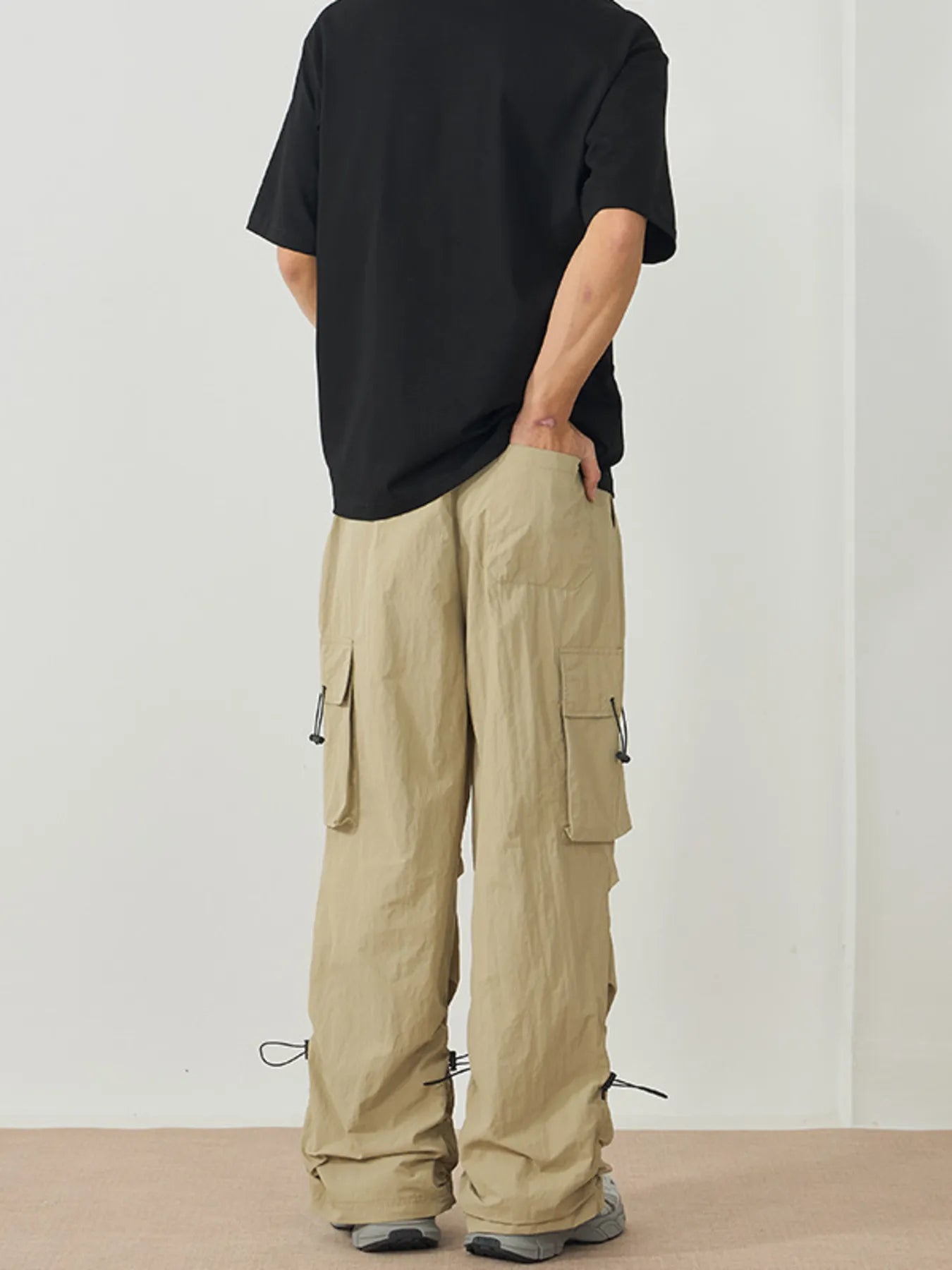 NEWYORKLISTED ATLAS MEN's Collection: Person wearing beige cargo pants and a black shirt on a plain background