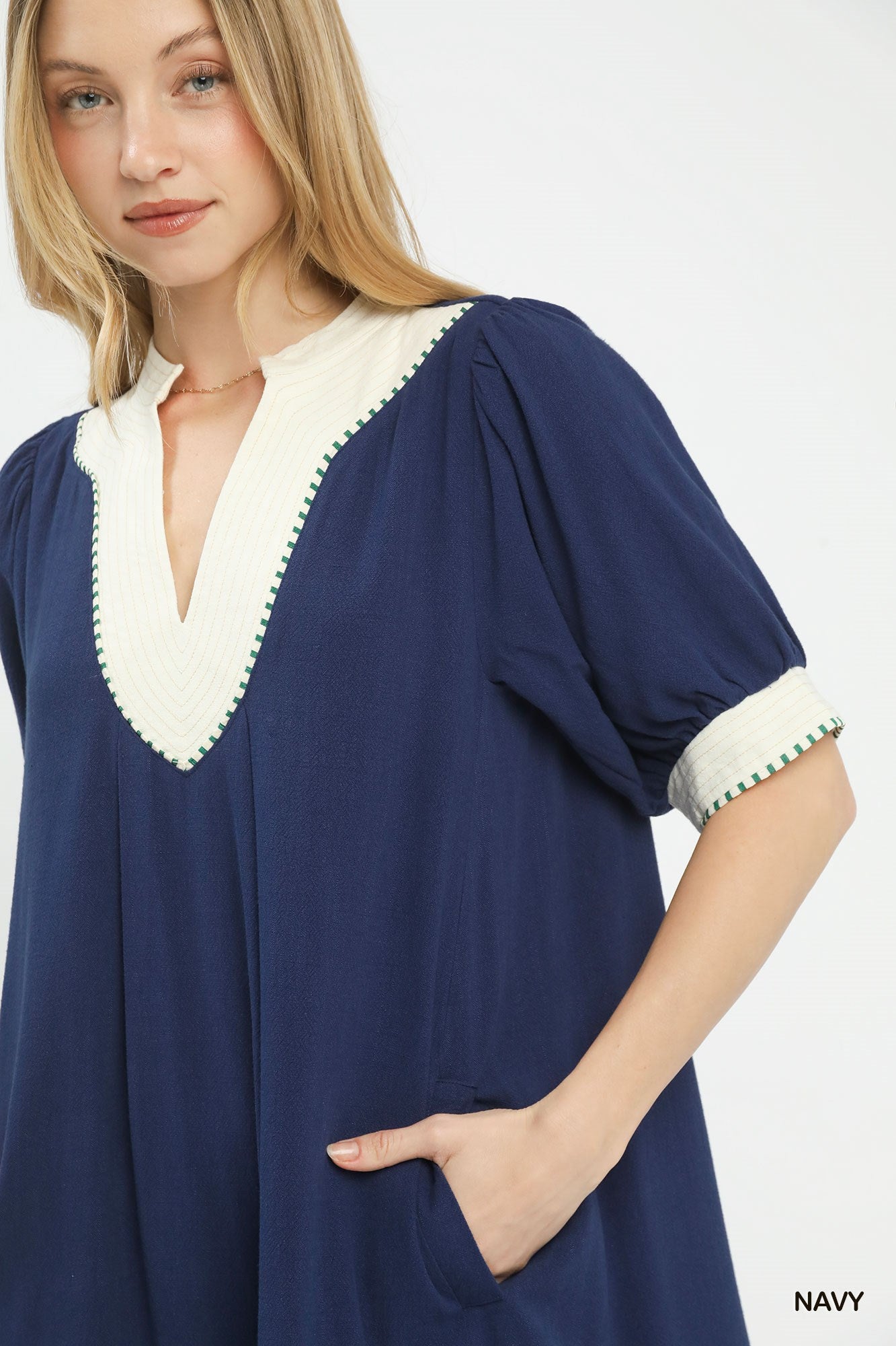 NEWYORKLISTED STYLE COLLECTION: Woman wearing a navy blue dress with white trim on a white background