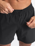 NEWYORKLISTED ATLAS MEN'S COLLECTION: Person adjusting the waistband of black shorts on a plain background