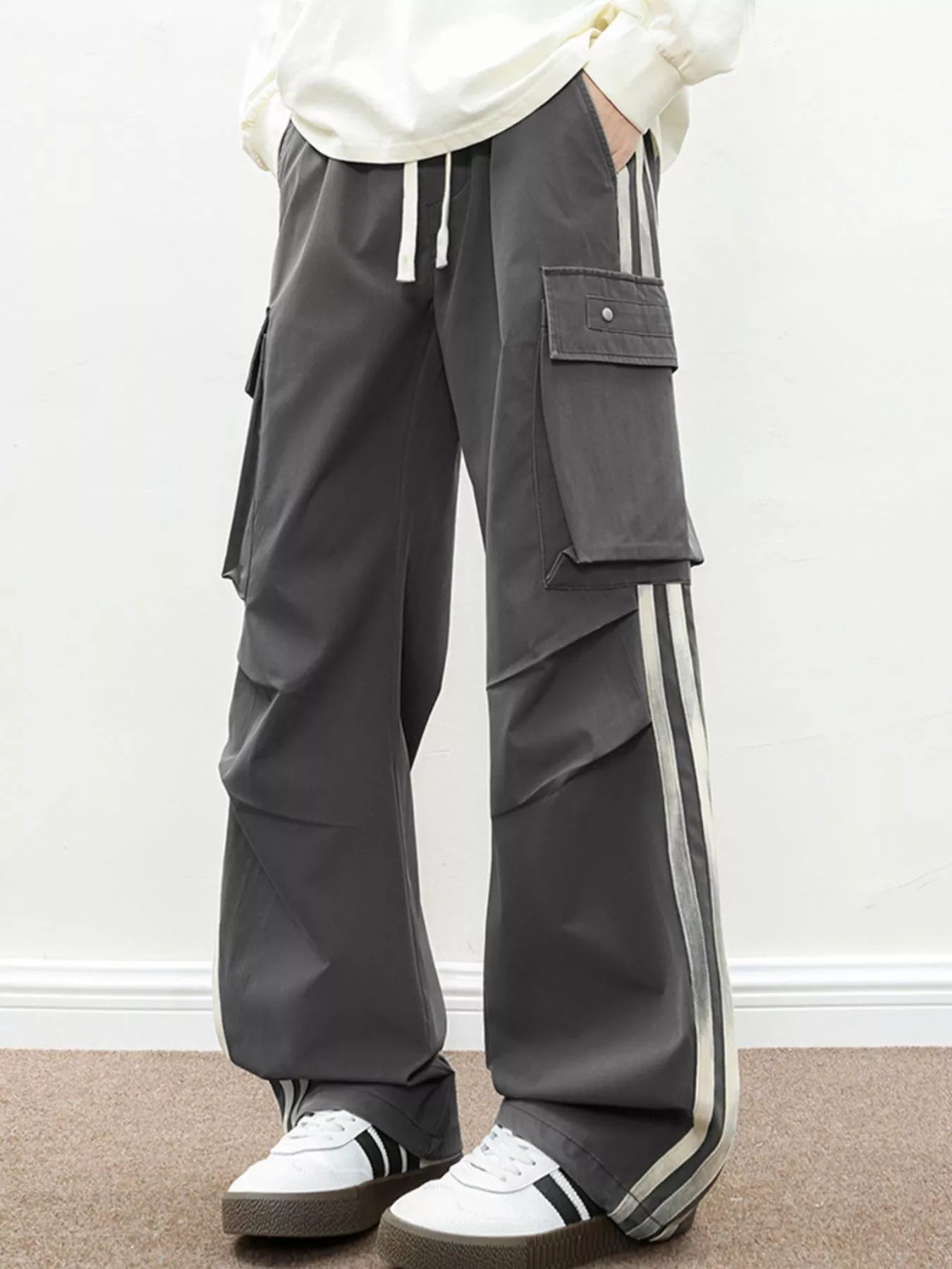 NEWYORKLISTED ATLAS MEN's COLLECTION: Person wearing gray cargo pants with white stripes on a plain background