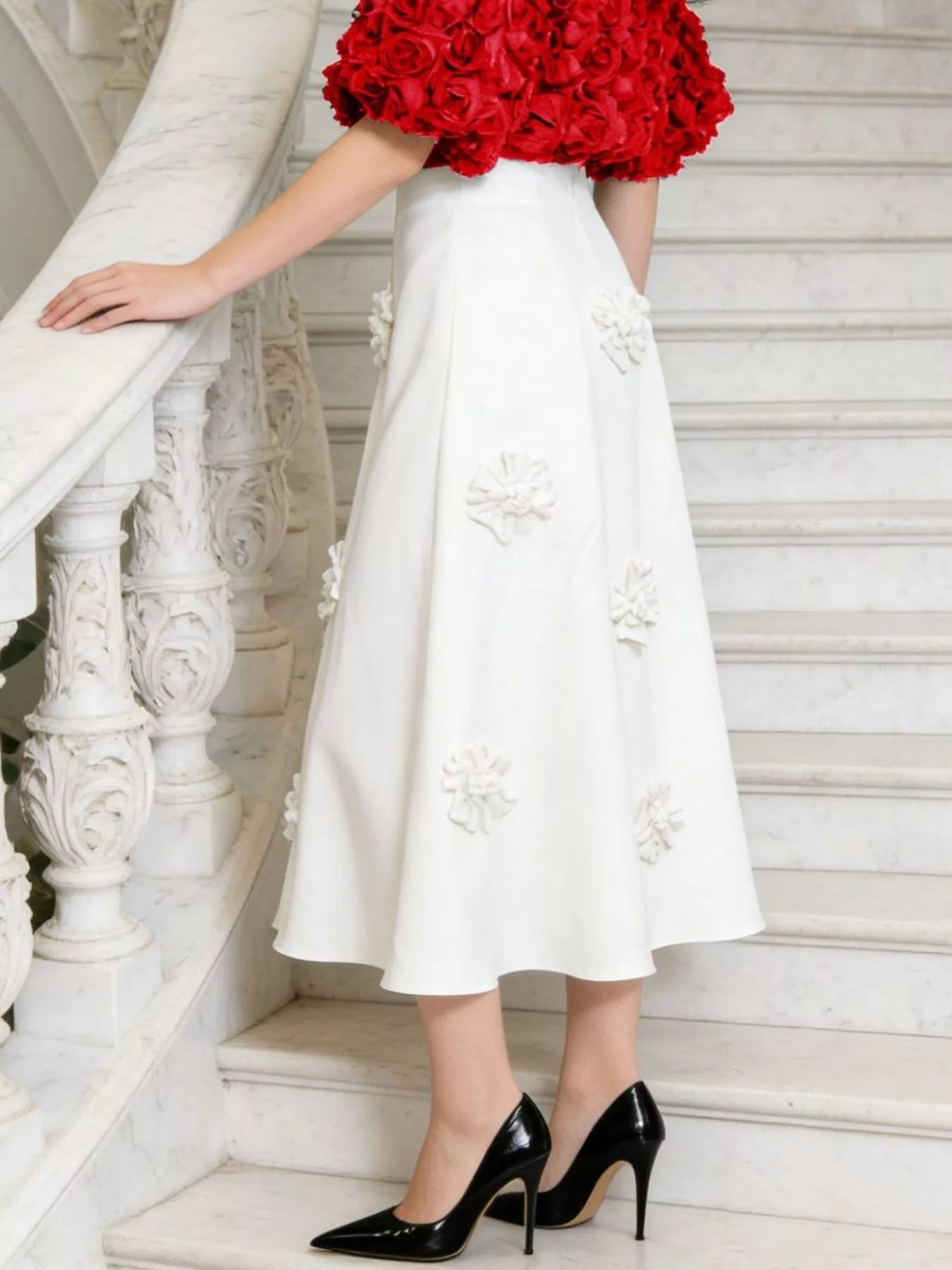 NEWYORKLISTED STYLE COLLECTION: Person wearing a white dress with floral embroidery and black high heels on a staircase.