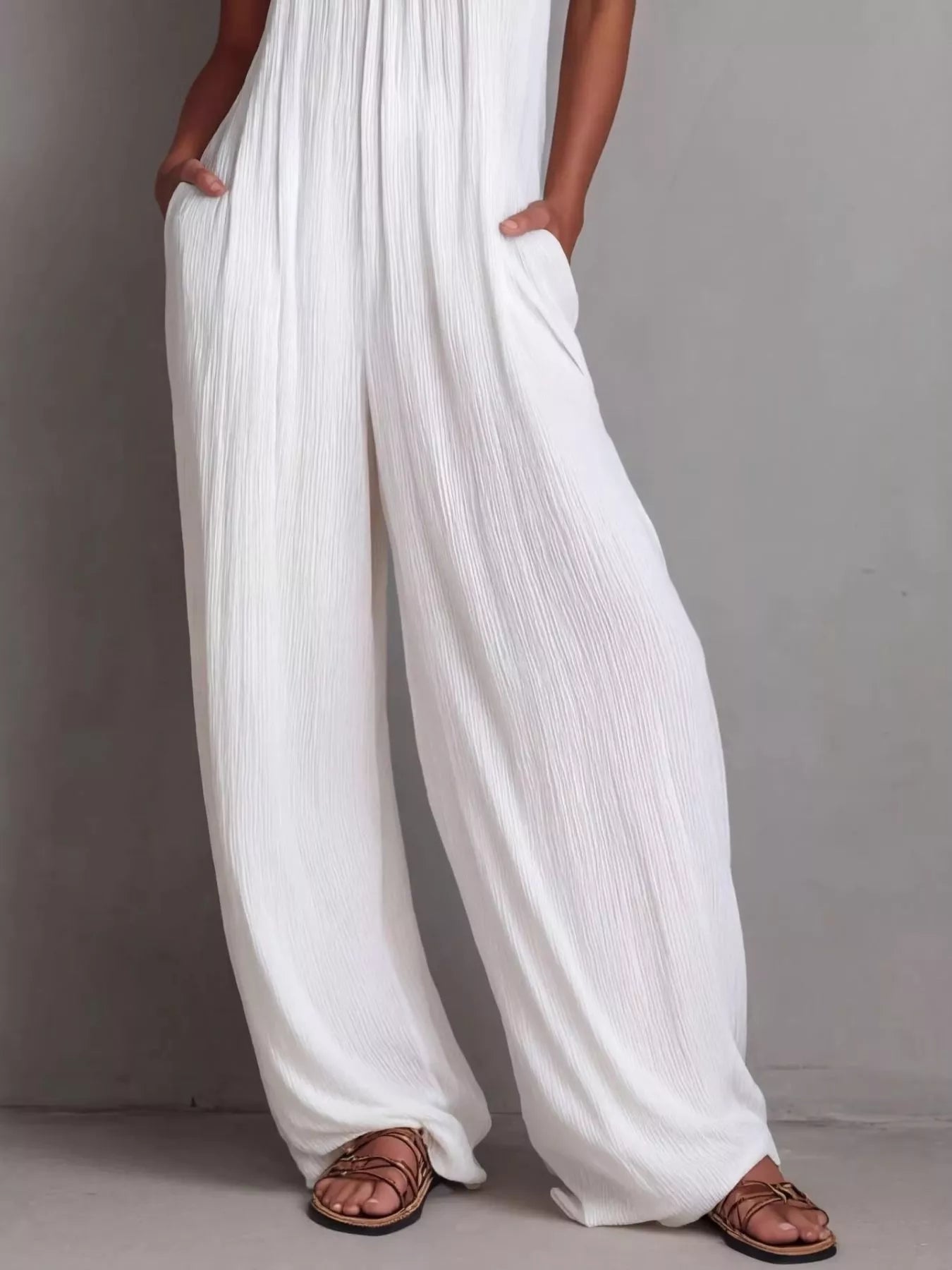 NEWYORKLISTED STYLE COLLECTION: White pleated pants worn by a person on a gray background