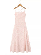NEWYORKLISTED STYLE COLLECTION: Pink dress with criss-cross straps on a hanger against a white background