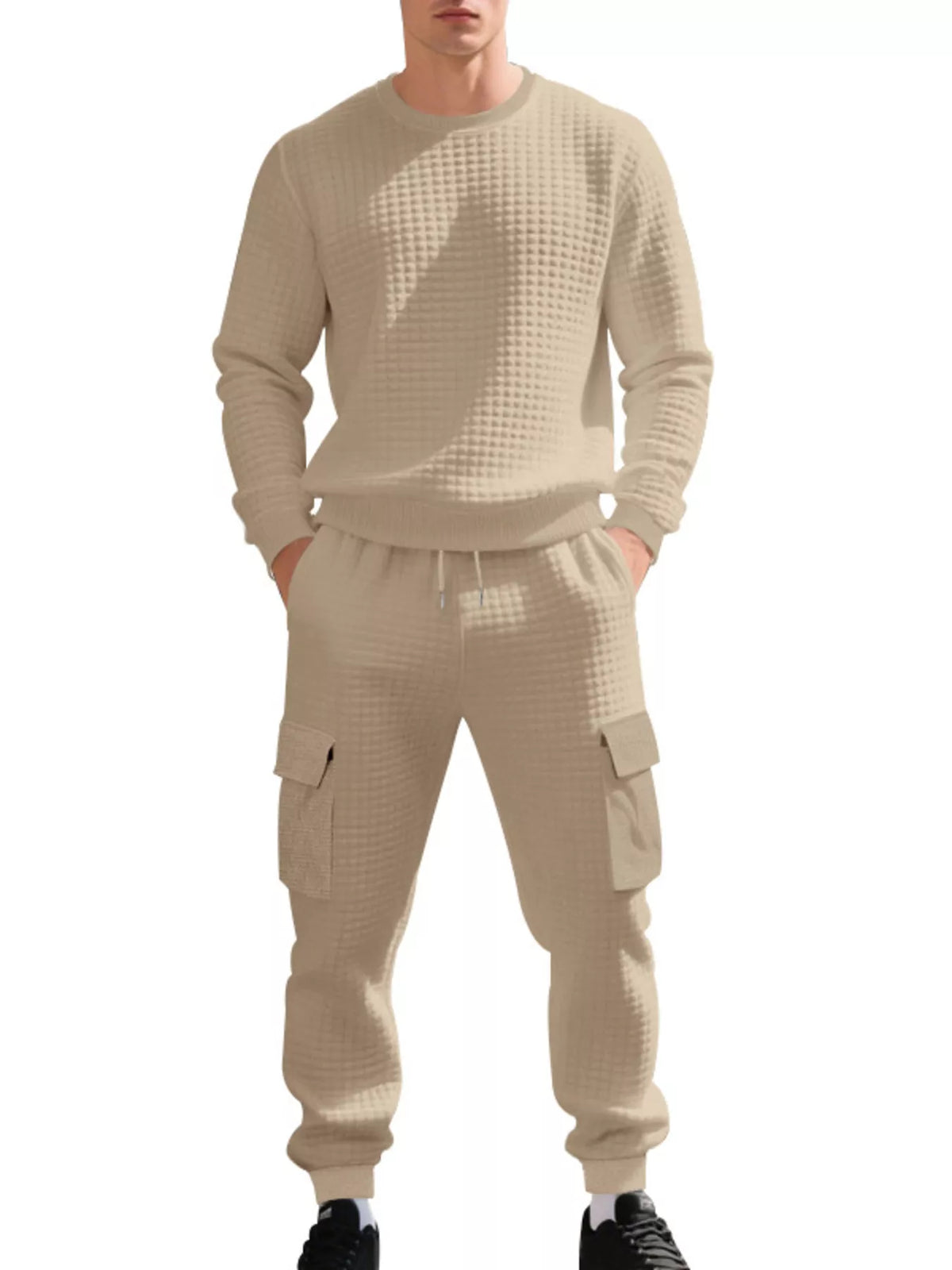 NEWYORKLISTED ATLAS MEN'S COLLECTION: A man wearing a matching beige waffle-knit lounge set, consisting of a long-sleeve crewneck sweatshirt and jogger pants with cargo pockets, shown against a plain white background.