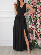 NEWYORKLISTED STYLE COLLECTION: Woman wearing a black dress with a slit, standing next to a floral arrangement.