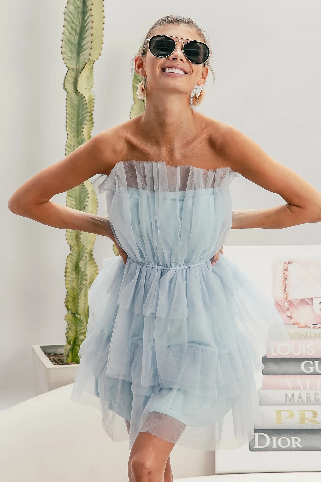 NEWYORKLISTED STYLE COLLECTION: Sleeveless Layered Organza Dress Woman wearing a light blue strapless dress with sunglasses indoors.