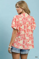 NEWYORKLISTED STYLE COLLECTION: Woman wearing a floral pink blouse with ruffled sleeves on a light blue background