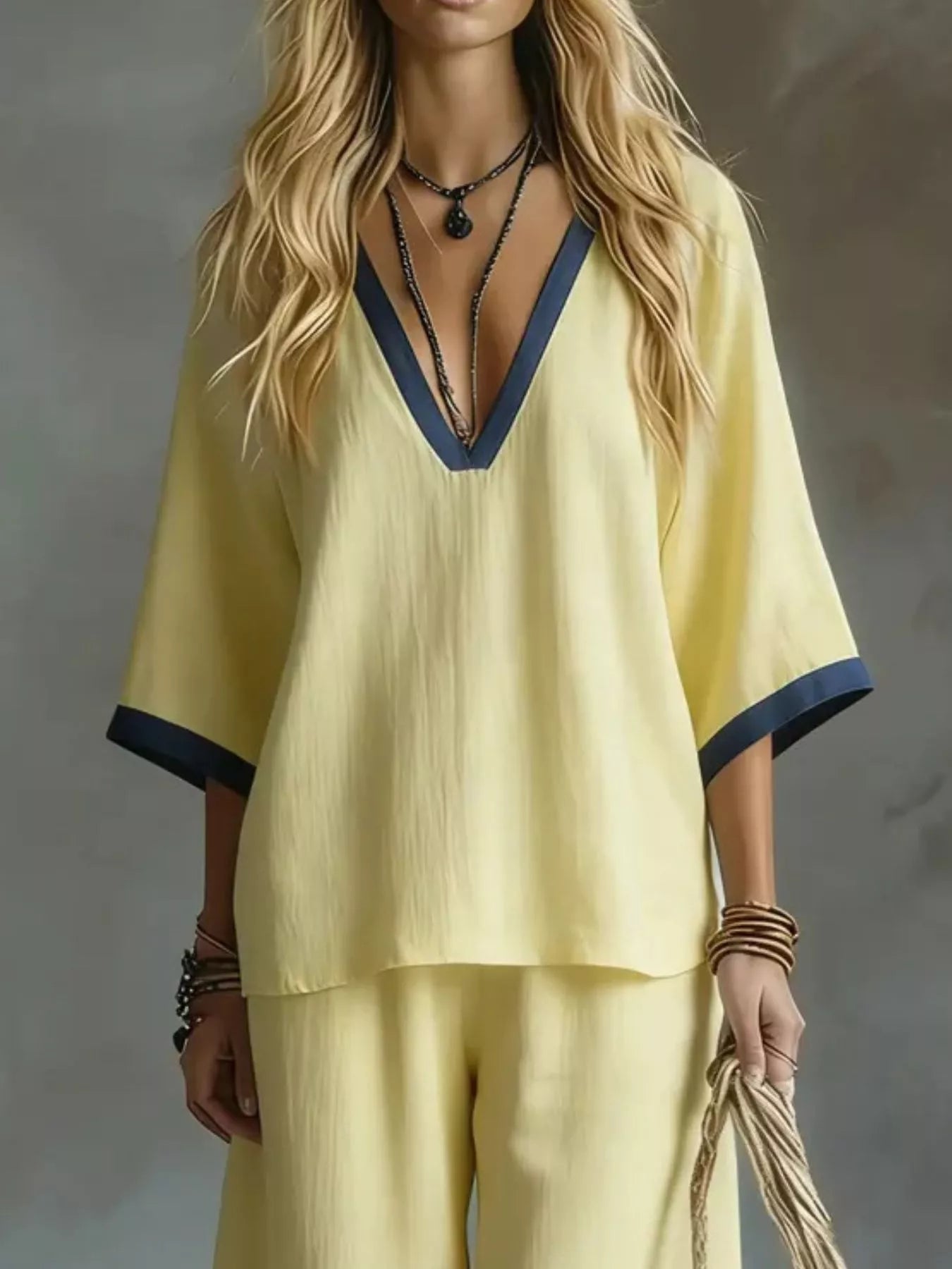 NEWYORKLISTED STYLE COLLECTION: Woman wearing a yellow outfit with blue trim against a gray background