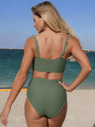 Woman wearing a green bikini set on a beach with ocean in the background