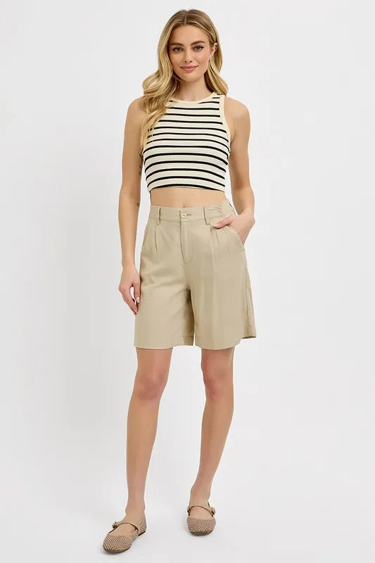 NEWYORKLISTED STYLE COLLECTION: Woman wearing a striped crop top and beige shorts on a white background