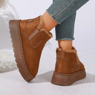 NEWYORKLISTED SHOE COLLECTION: A pair of women's brown suede-look slip-on boots with plush faux-fur lining, shown on a model's feet with frayed-hem blue jeans against a clean white background.