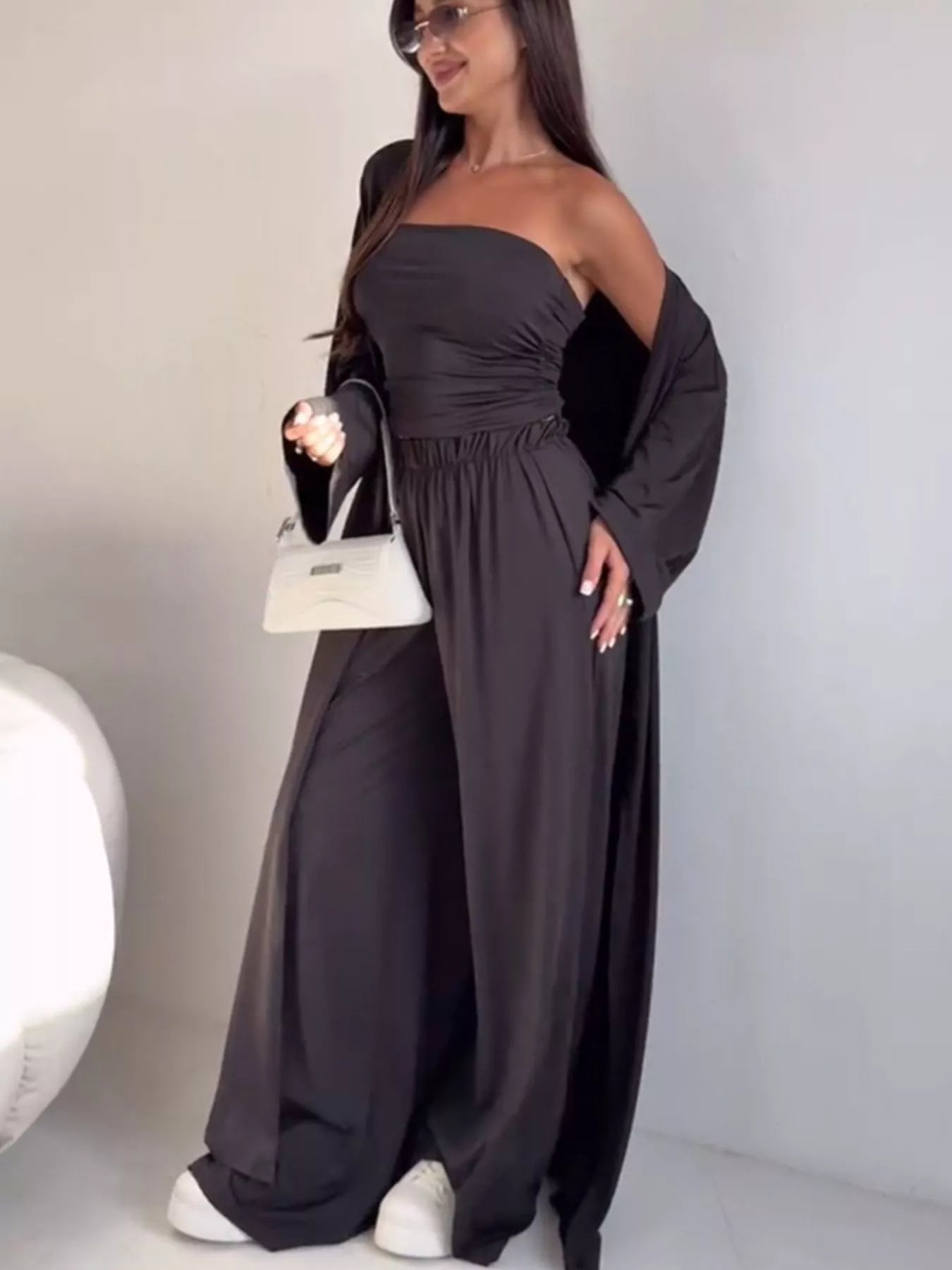 NEWYORKLISTED COMFORT COLLECTION: Woman wearing a dark gray off-shoulder dress with long sleeves against a plain background