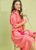 NEWYORKLISTED STYLE COLLECTION: Woman in a pink floral dress holding flowers against a light green background