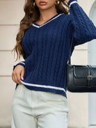 NEWYORKLISTED STYLE COLLECTION: Woman wearing a blue cable knit sweater and white pants, holding a black handbag.