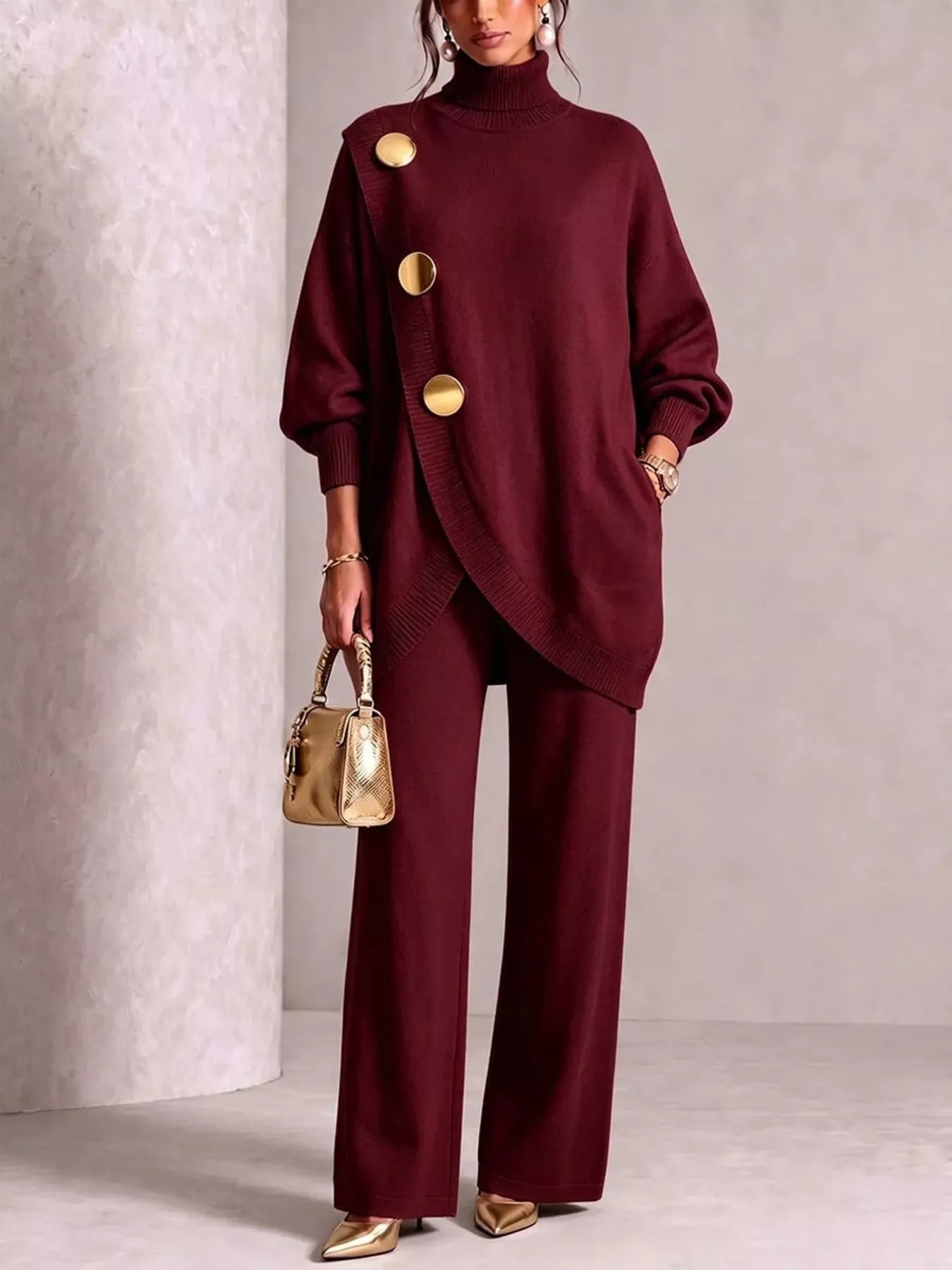 NEWYORKLISTED STYLE COLLECTION: A model wears a matching burgundy knit turtleneck sweater and wide-leg trousers set with large gold-tone decorative buttons. She is holding a small metallic gold handbag and wearing gold pointed shoes, set against a neutral textured studio backdrop.