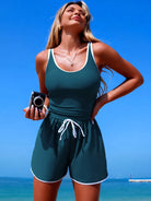 NEWYORKLISTED STYLE COLLECTION: Woman in a teal romper standing on a beach with clear blue sky