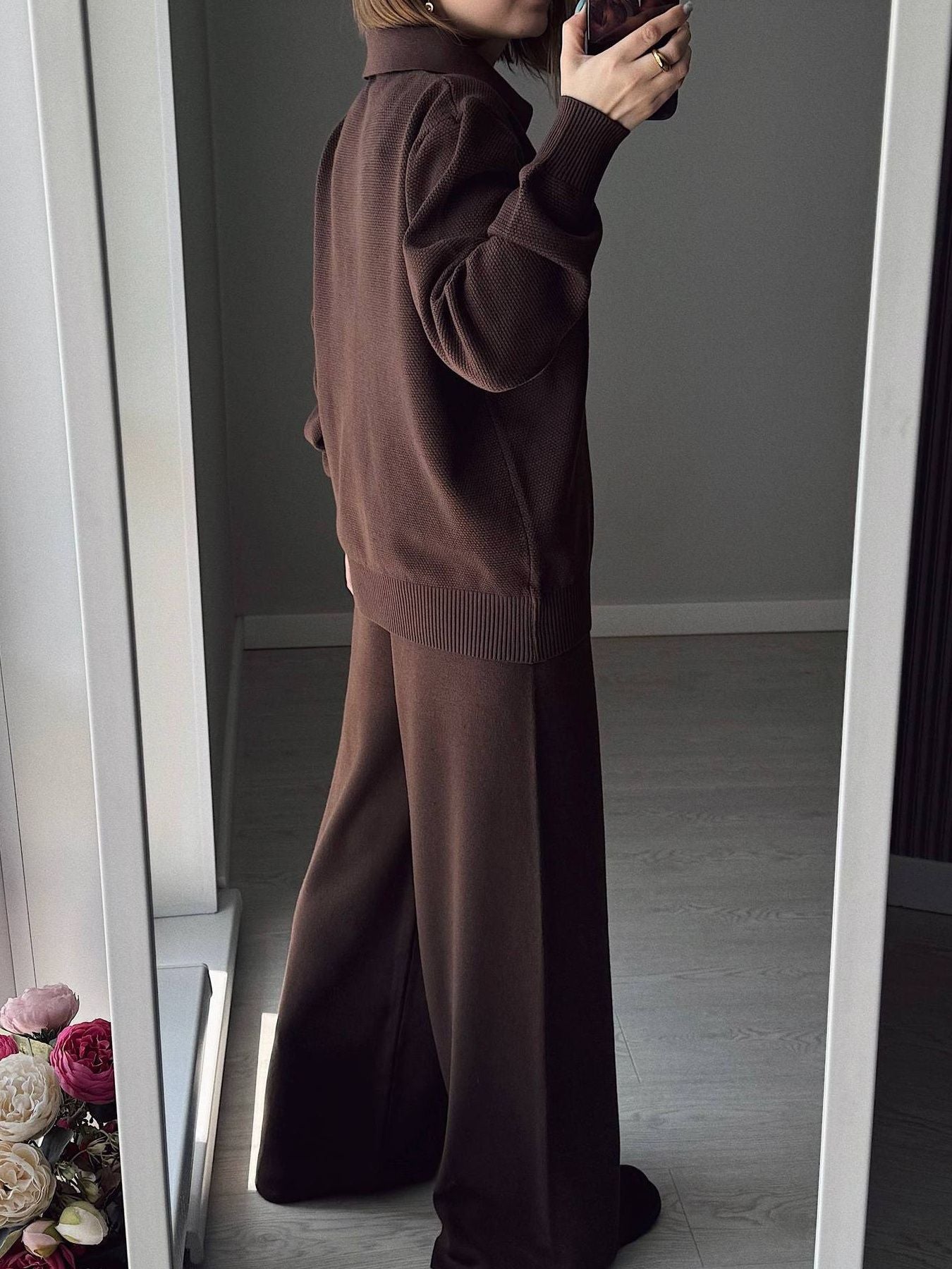 NEWYORKLISTED Comfort Collection: Person wearing a brown outfit taking a mirror selfie in a room.