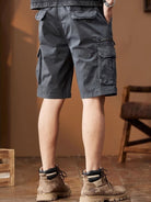 NEWYORKLISTED ATLAS MEN's COLLECTION: Person wearing gray cargo shorts and brown boots indoors.