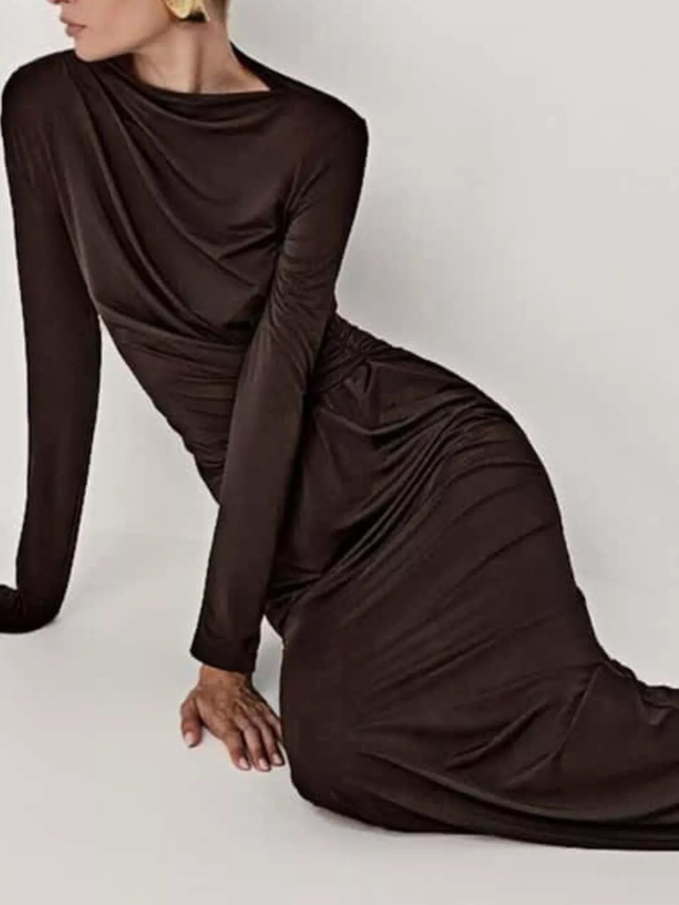 NEWYORKLISTED STYLE COLLECTION: Woman wearing a brown long-sleeve dress sitting on a white background