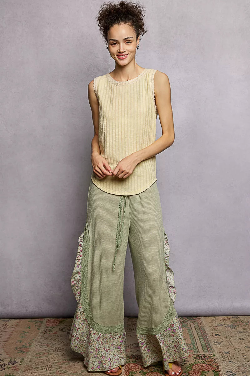 NEWYORKLISTED STYLE COLLECTION: Woman wearing a sleeveless top and wide-leg pants with floral details against a gray background