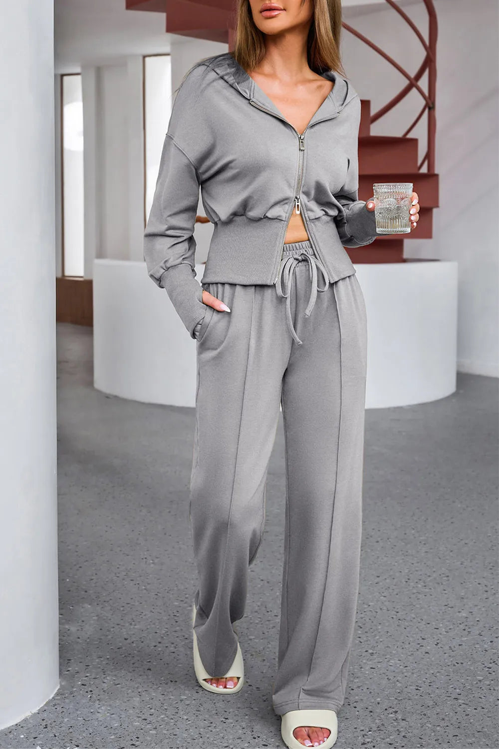 NEWYORKLISTED ACTIVEWEAR COLLECTION: Woman wearing a gray tracksuit in an indoor setting