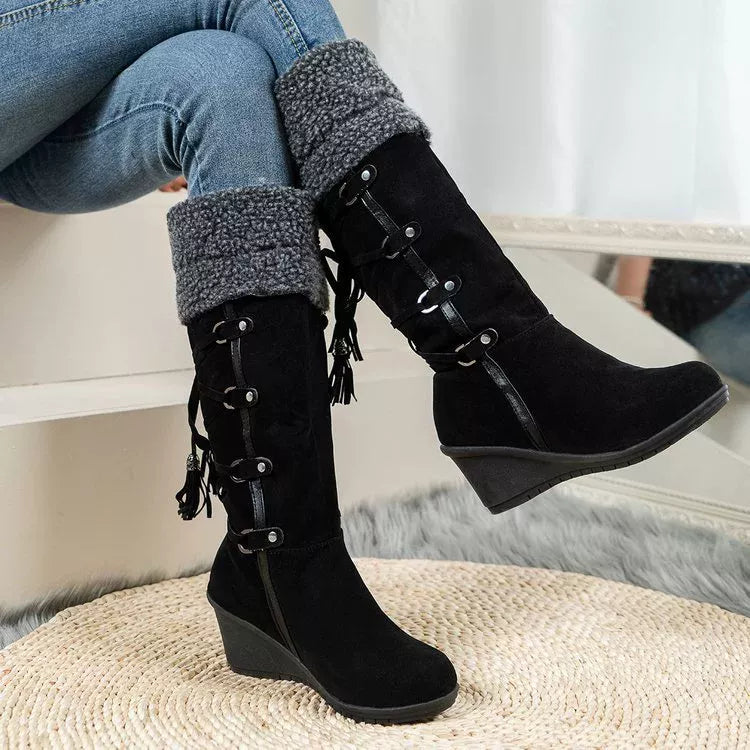 NEWYORKLISTED SHOE COLLECTION: Black wedge boots with lace-up design worn by a person sitting on a white surface.