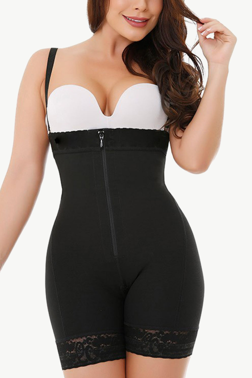 NEWYORKLISTED Intimate Apparel: Woman wearing a black shapewear garment with a white bra underneath on a white background