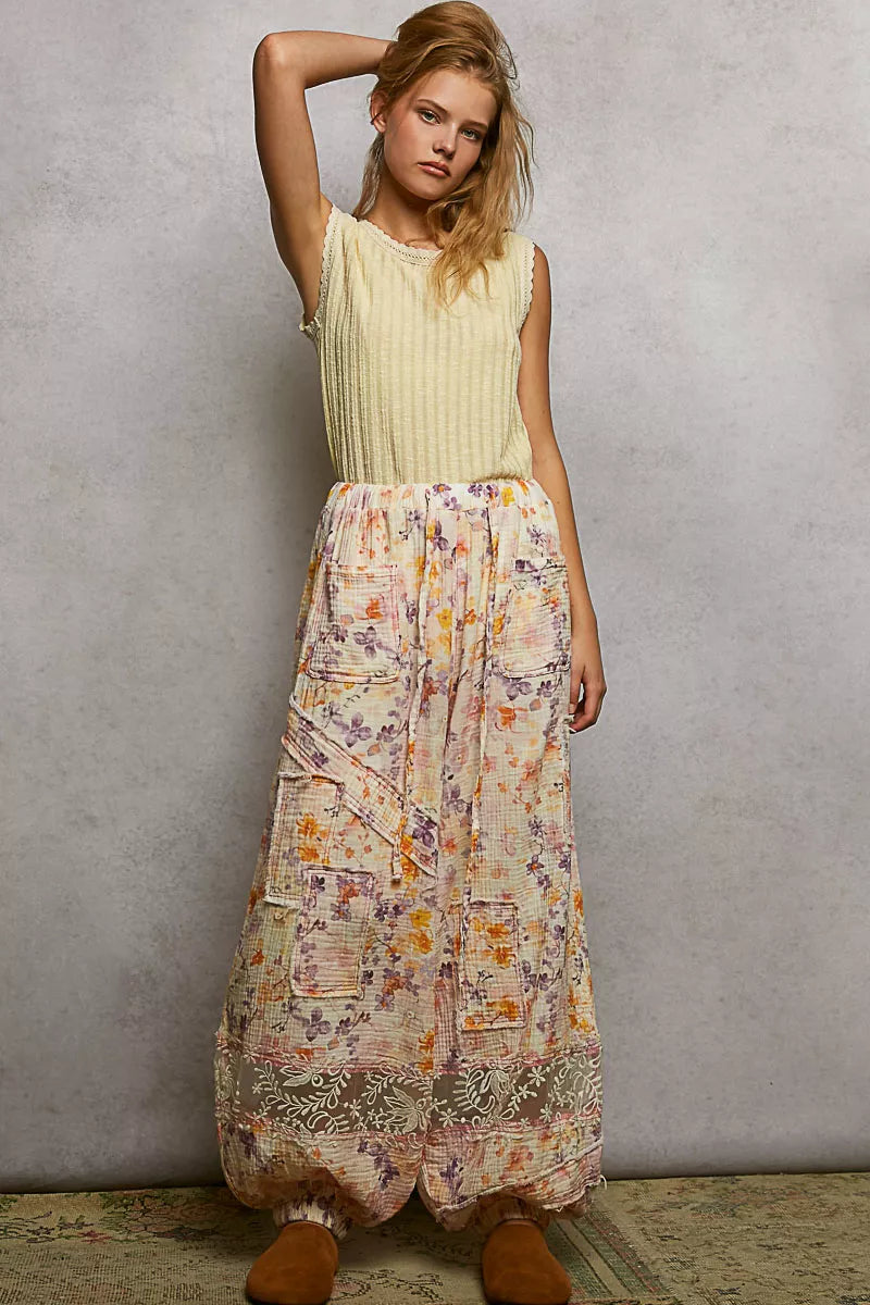 NEWYORKLISTED STYLE COLLECTION: Woman wearing a light-colored sleeveless top and a long, patterned skirt against a plain background.