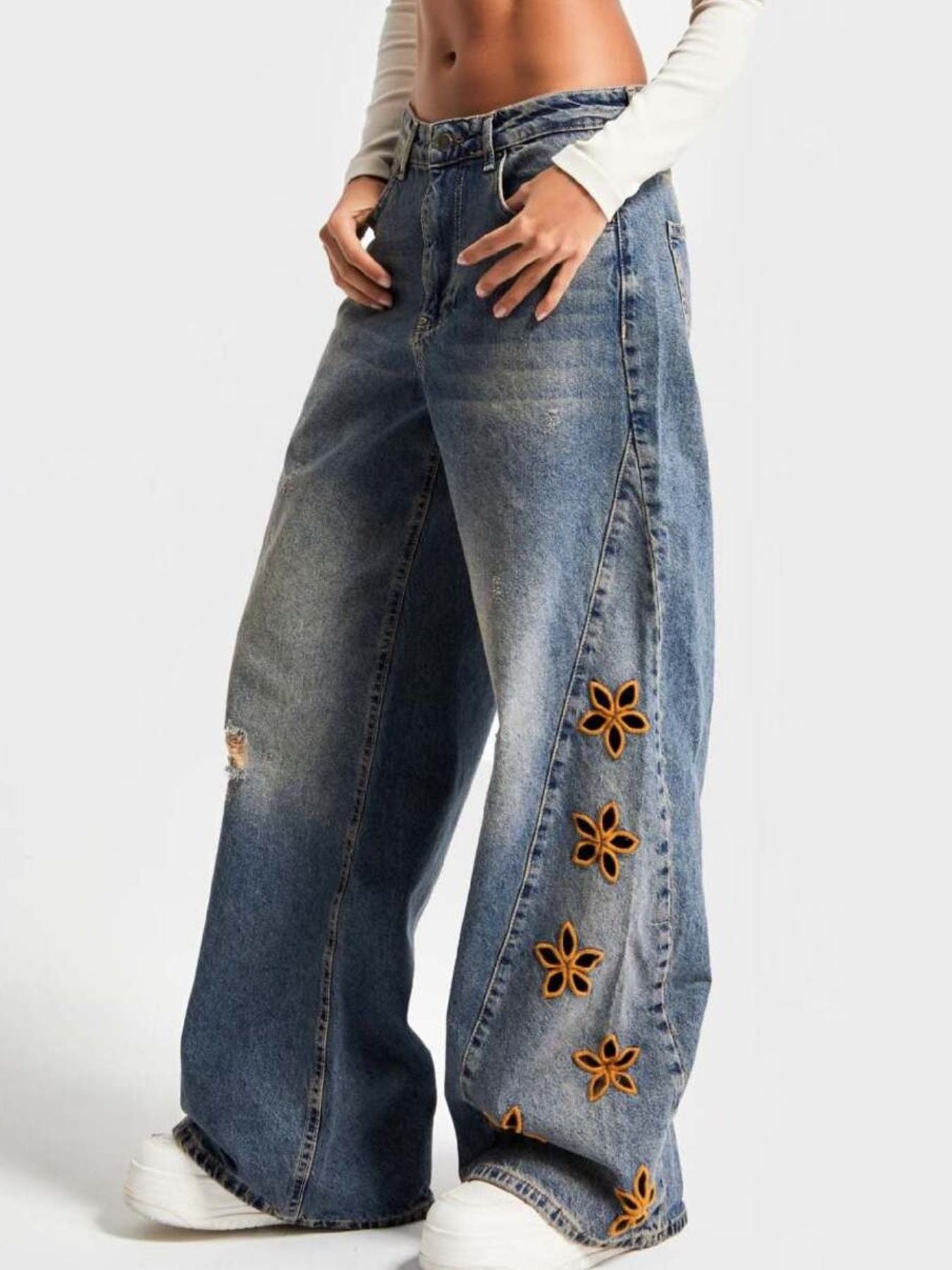 NEWYORKLISTED STYLE COLLECTION: Blue jeans with floral embellishments on a white background
