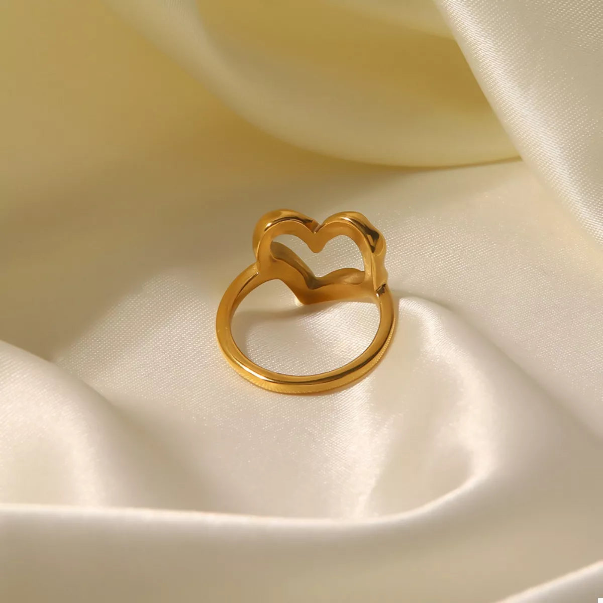 NYLD Glamour Collection by NEWYORKLISTED: Gold heart-shaped ring on a soft beige fabric background