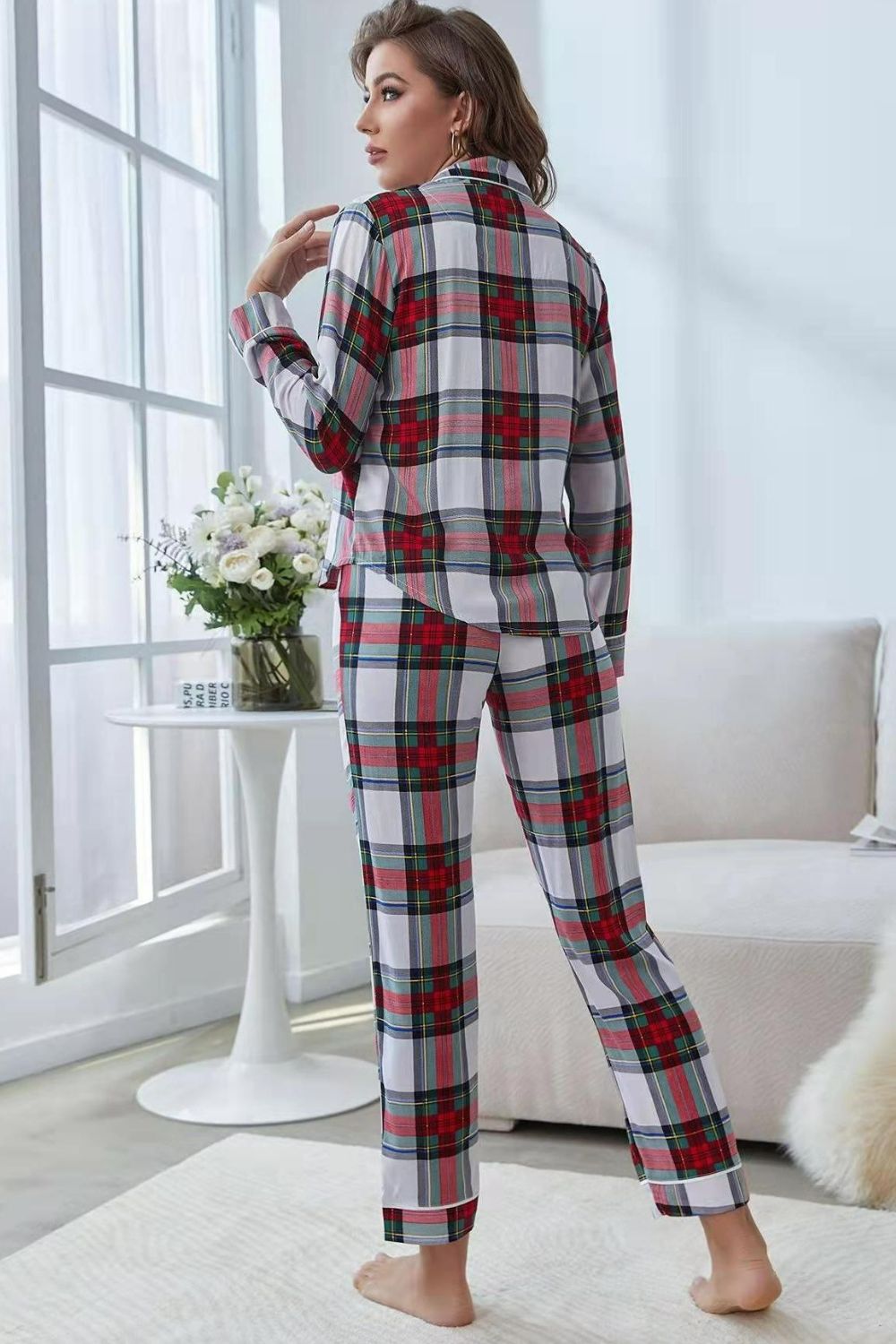 NEWYORKLISTED Intimate Apparel: Woman wearing a plaid pajama set in a bright room with a vase of flowers on a table.