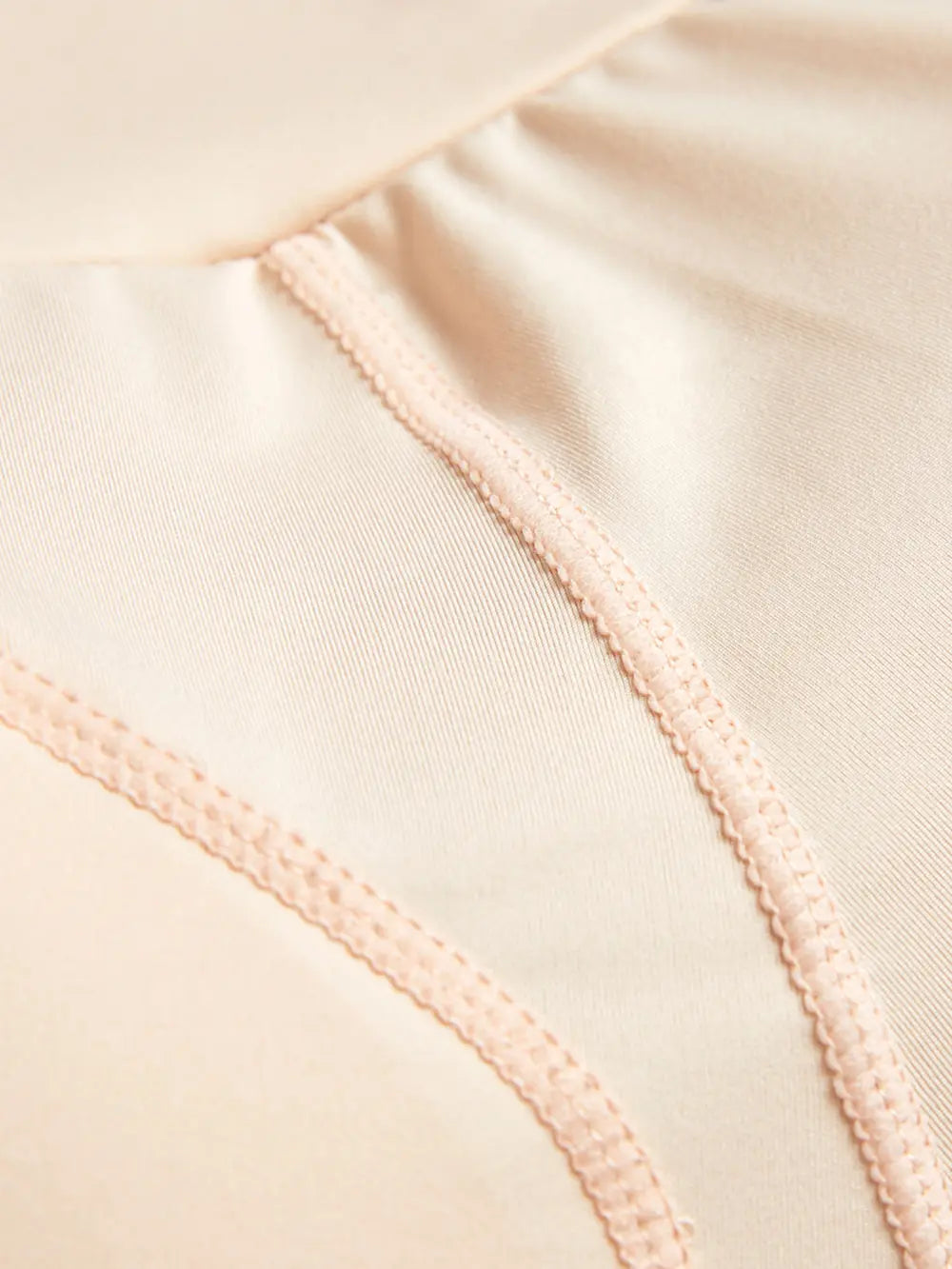 NEWYORKLISTED Intimate Apparel: Close-up of beige fabric with a focus on stitching detail