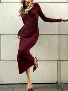 NEWYORKLISTED STYLE COLLECTION: Woman wearing a burgundy dress against a light-colored wall.