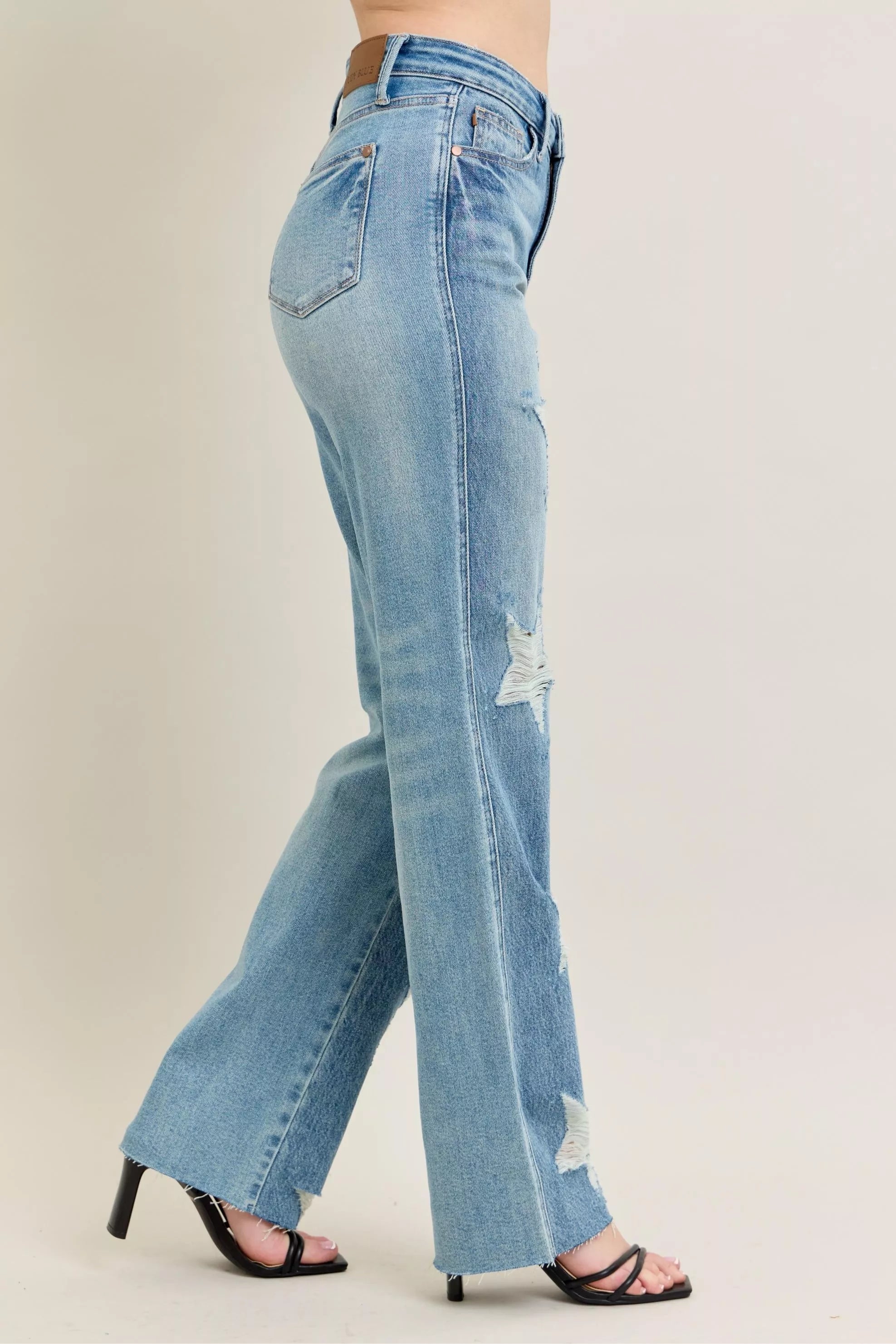 NEWYORKLISTED STYLE COLLECTION: Light blue jeans with a slight distressed look worn by a person on a beige background