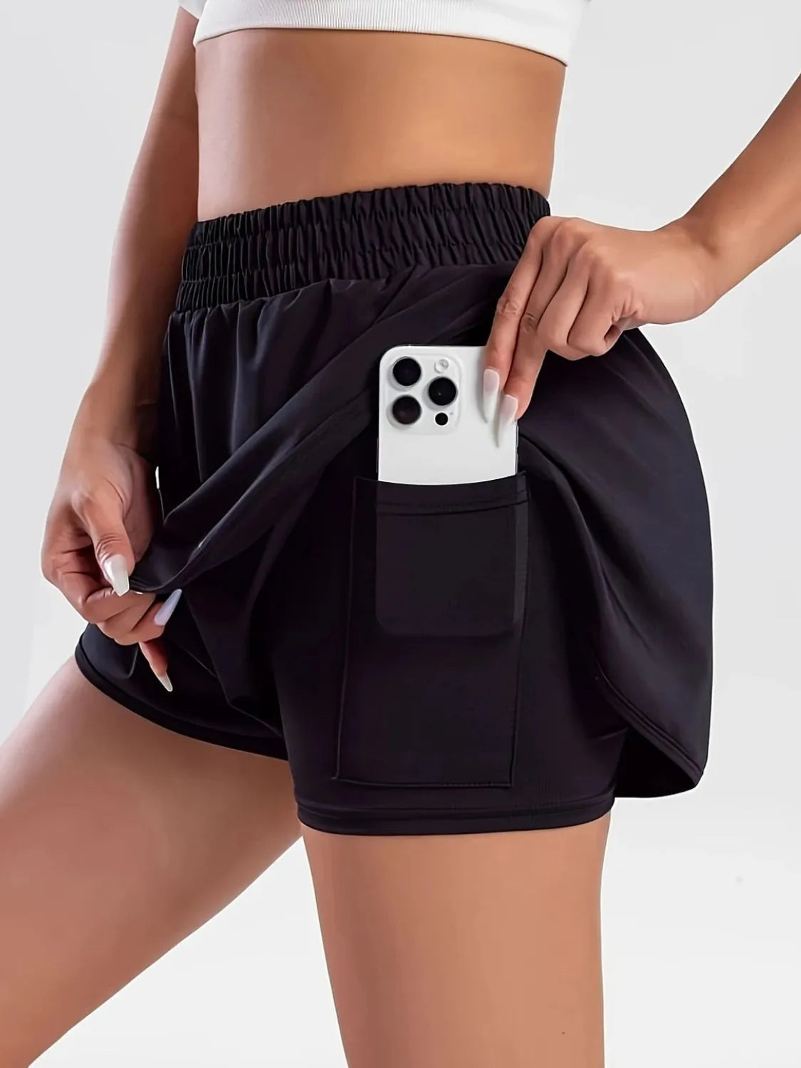 NEWYORKLISTED Activewear: Person wearing black shorts with a pocket holding a phone on a white background