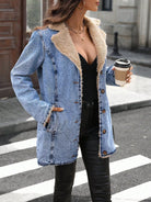 NEWYORKLISTED STYLE COLLECTION: A woman wearing a light blue denim jacket with a beige sherpa lining, styled with a black top and black pants while holding a coffee cup on a city street.