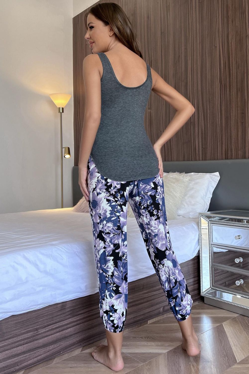 NEWYORKLISTED Intimate Apparel: Woman wearing a gray tank top and floral leggings in a bedroom setting.