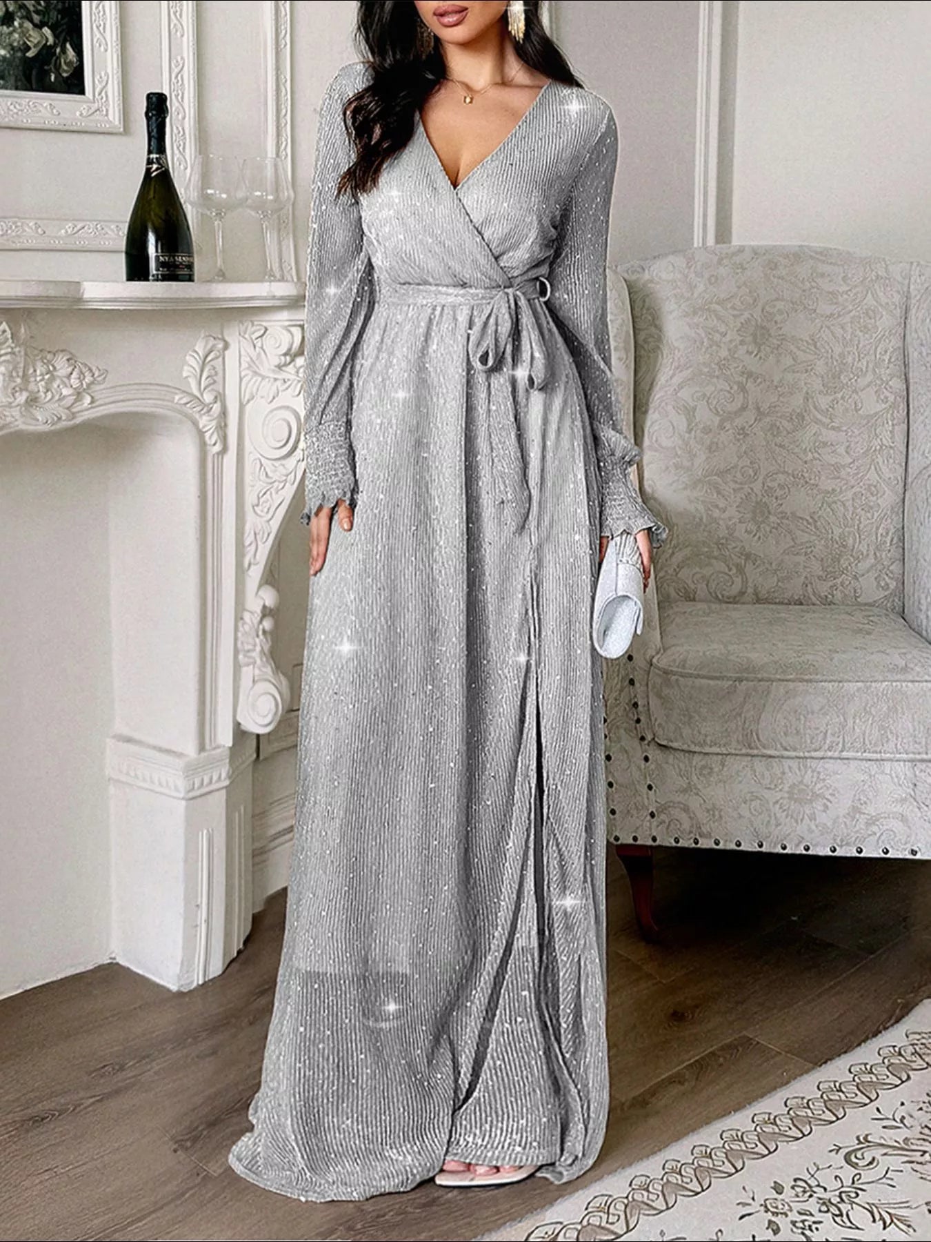 NEWYORKLISTED STYLE COLLECTION: Woman wearing a sparkly gray dress in a room with a fireplace and chair.