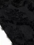 NEWYORKLISTED STYLE COLLECTION: Close-up of black textured fabric with frayed edges on a dark background