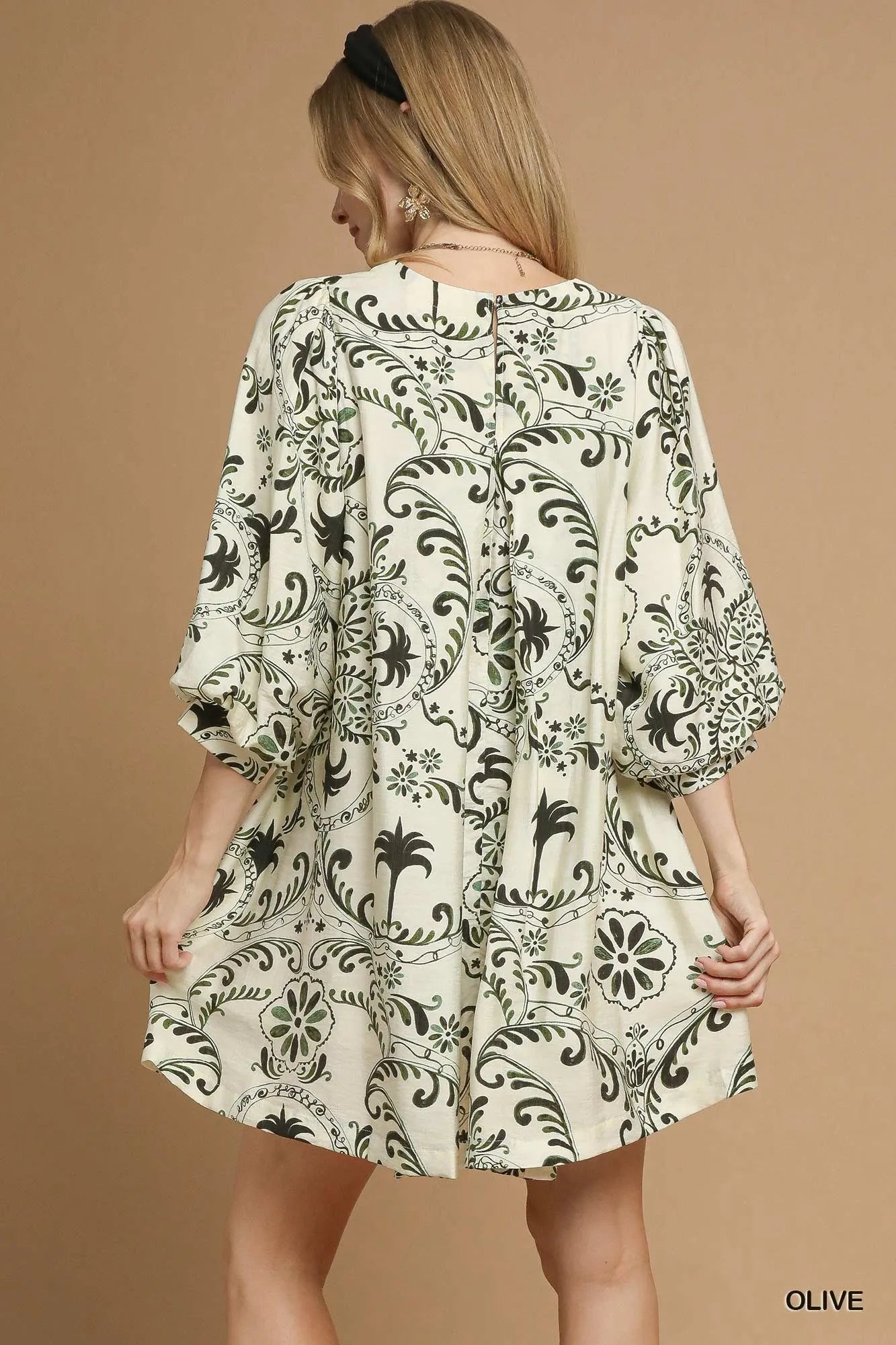 NEWYORKLISTED STYLE COLLECTION: Woman wearing a patterned dress on a beige background