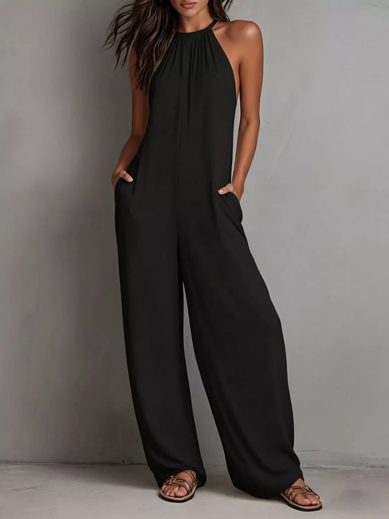 NEWYORKLISTED STYLE COLLECTION: Woman wearing a black jumpsuit against a gray background